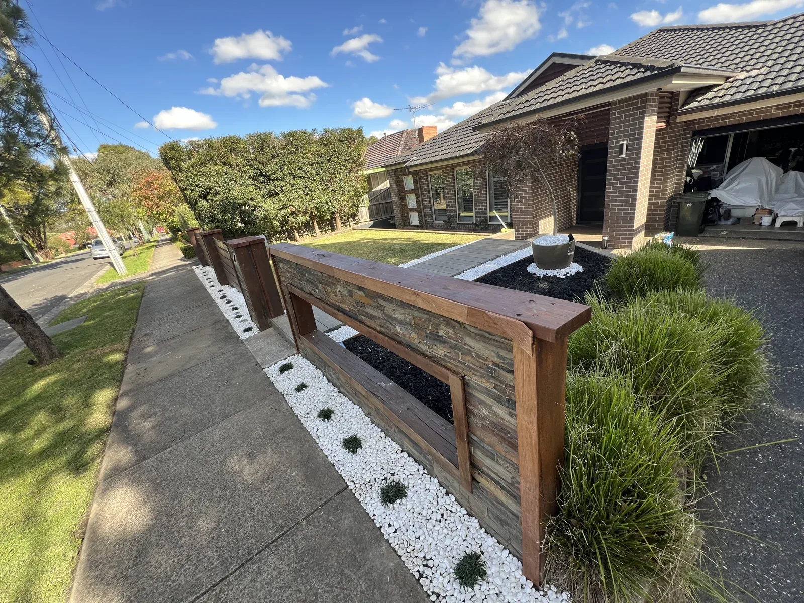 Front garden with lawn, planting and a timber-framed stone entrance