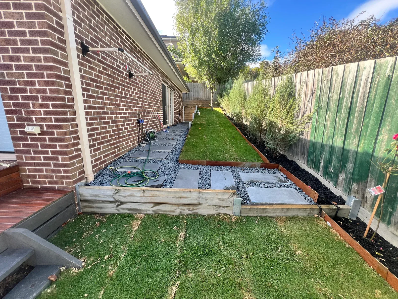 Stepping-stone paths, lawn and planted borders in a finished side garden